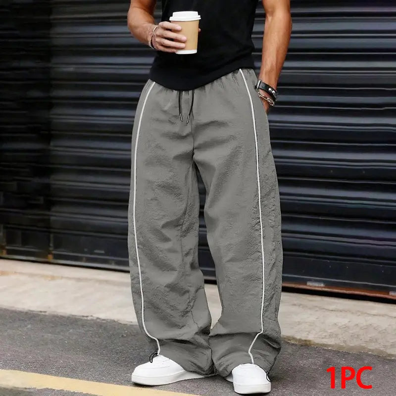 Men’s summer black-and-red quick-dry wide-leg pants with side stripes and a drawstring waist; breathable fabric with a slight wrinkle texture, loose straight cut, side stripe detailing, adjustable cuffs at the leg openings. Suitable for jogging, fitness,